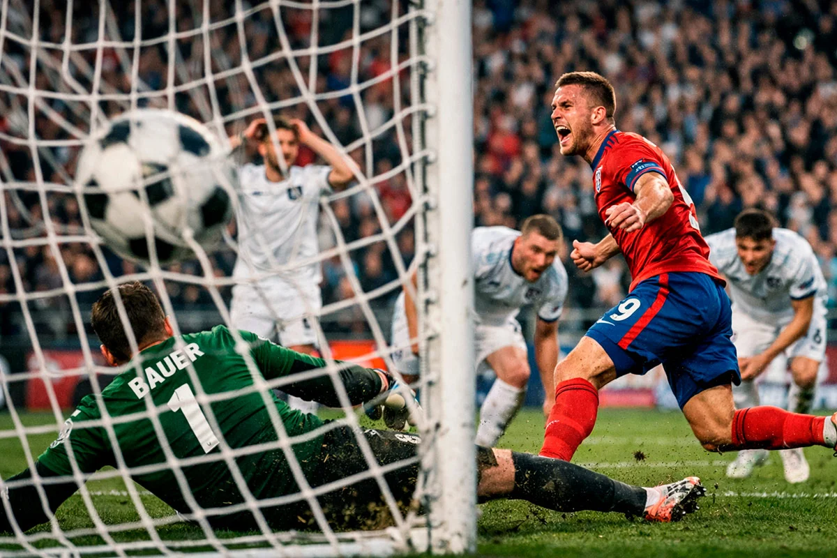 Balón de fútbol entrando en la red de una portería con la grada iluminada de fondo