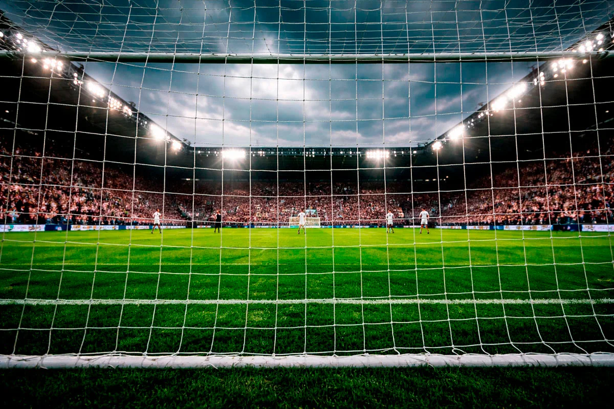 Estadio de fútbol inglés con césped verde intenso bajo un cielo nublado típico de Inglaterra